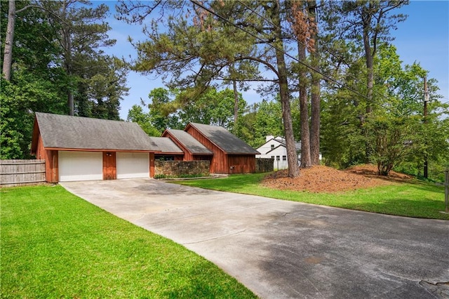 view of front facade with concrete driveway, an attached garage, fence, and a front yard