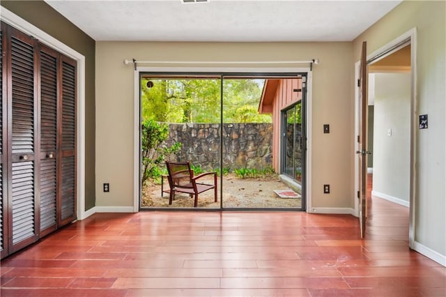 doorway to outside with baseboards and wood finished floors