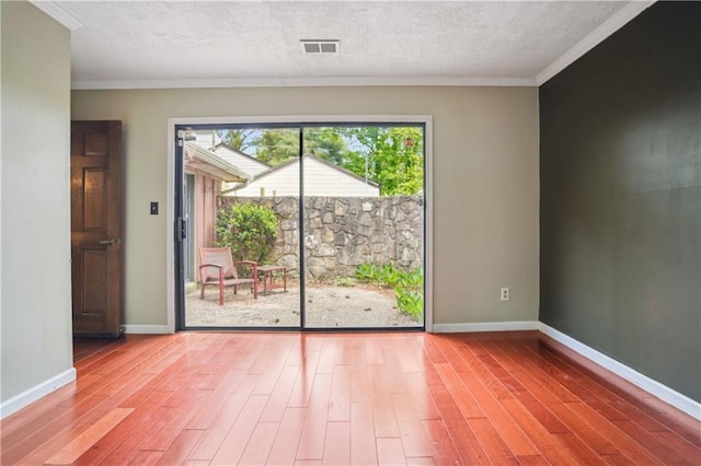 spare room featuring visible vents, ornamental molding, baseboards, and wood finished floors