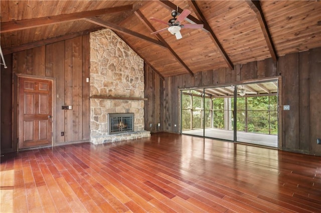 unfurnished living room with wooden walls, hardwood / wood-style floors, a ceiling fan, wooden ceiling, and beamed ceiling