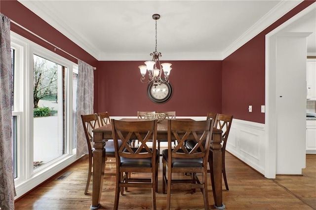 dining room featuring a notable chandelier, hardwood / wood-style flooring, and ornamental molding