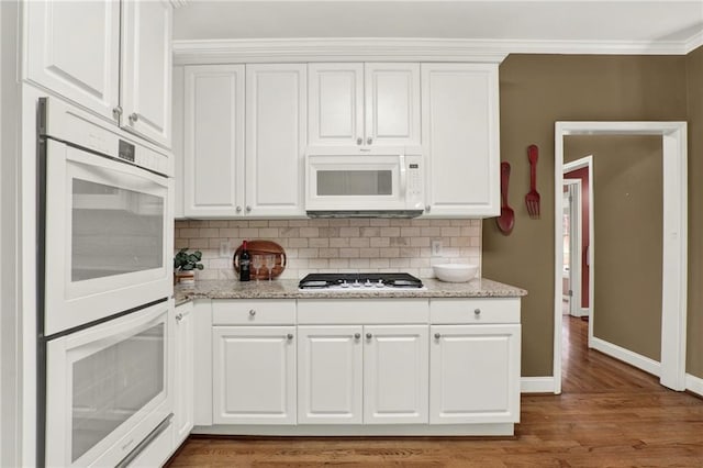 kitchen with crown molding, white cabinets, and white appliances