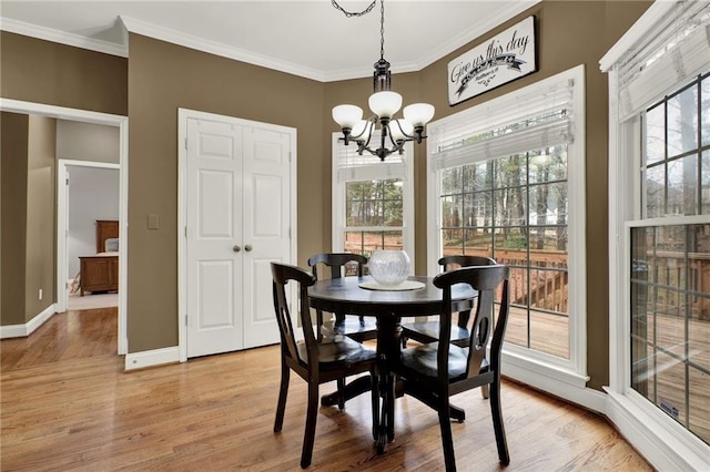 dining space featuring crown molding, a chandelier, and light hardwood / wood-style flooring