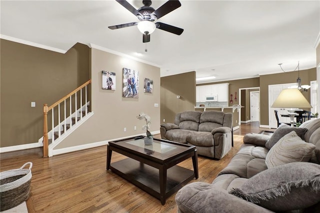 living room with hardwood / wood-style flooring, ceiling fan, and crown molding