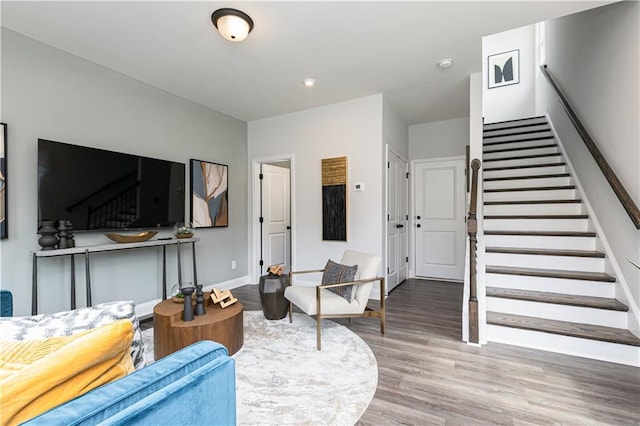 living area with stairway, wood finished floors, and baseboards