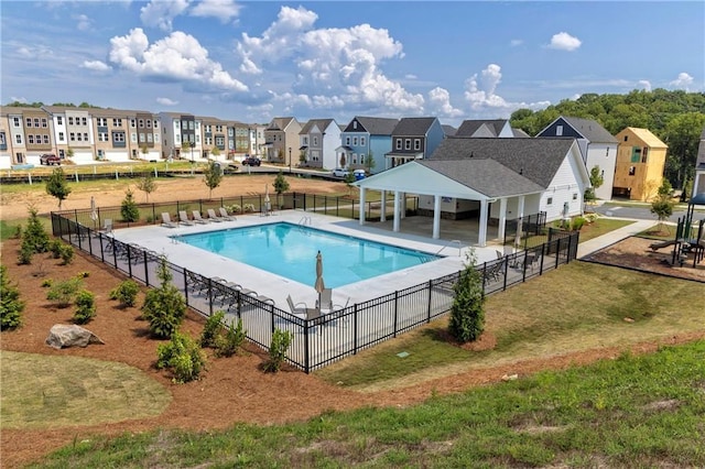 pool with a patio, fence, a gazebo, a lawn, and a residential view