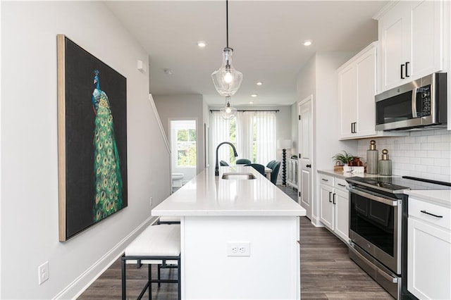 kitchen with a breakfast bar, a kitchen island with sink, a sink, tasteful backsplash, and stainless steel appliances