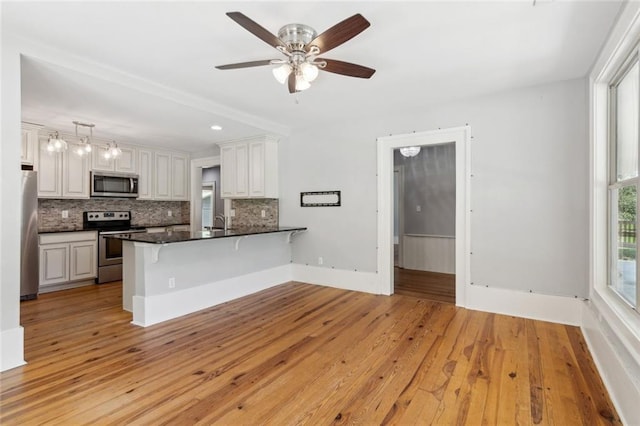 1382 6th Ave, Auburn, GA 30011 - kitchen featuring stainless steel appliances, decorative backsplash, a breakfast bar area, a peninsula, and light wood-style floors