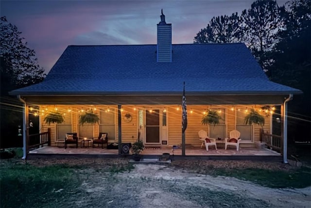 back house at dusk featuring a patio