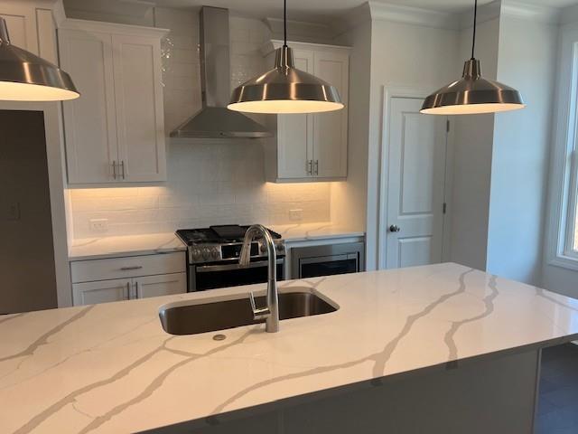 kitchen with white cabinets, a center island with sink, hanging light fixtures, sink, and stainless steel refrigerator with ice dispenser