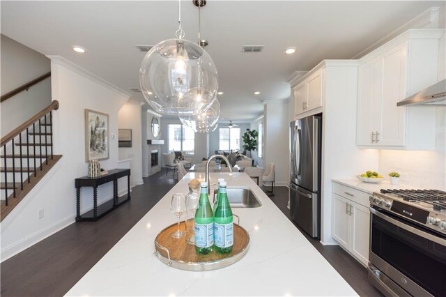 kitchen with dark wood-type flooring, crown molding, decorative light fixtures, white cabinets, and appliances with stainless steel finishes