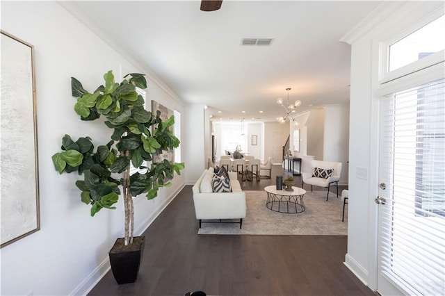 living room featuring dark hardwood / wood-style flooring, ornamental molding, and a chandelier