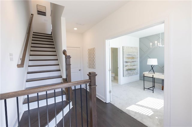 stairs featuring hardwood / wood-style floors and an inviting chandelier