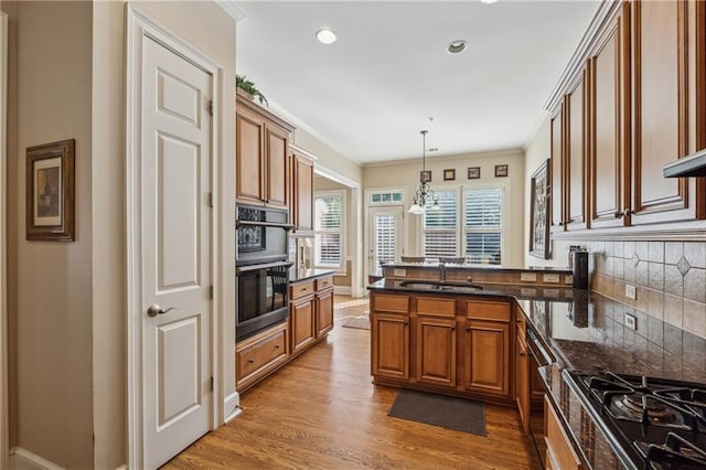 11715 Dancliff Trce, Alpharetta, GA 30009 - kitchen with a sink, brown cabinets, a peninsula, backsplash, and light wood-type flooring