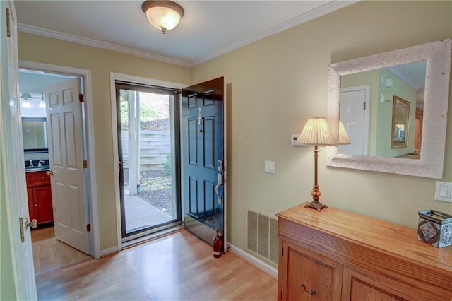 entrance foyer with light wood finished floors, visible vents, baseboards, and ornamental molding