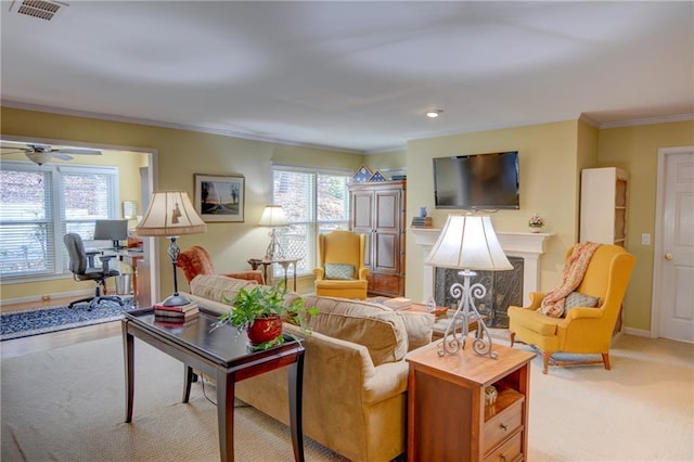 carpeted living area featuring visible vents, ornamental molding, a fireplace, baseboards, and ceiling fan