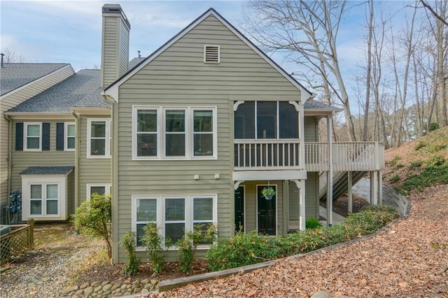 back of house featuring a wooden deck, a chimney, and a sunroom