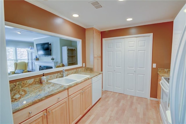 kitchen with white appliances, light brown cabinets, visible vents, a sink, and light wood-style floors