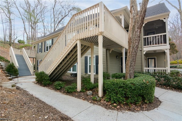 view of home's exterior featuring stairway, a ceiling fan, and a shingled roof