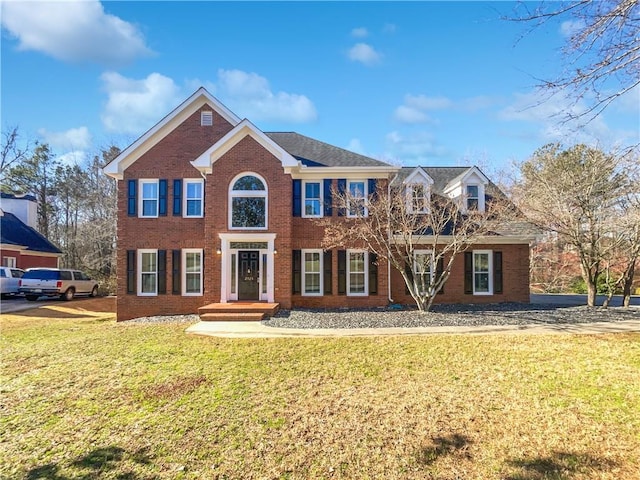 colonial house with a front lawn and brick siding