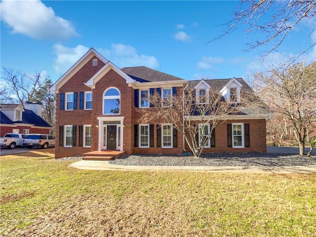 colonial house with a front yard and brick siding