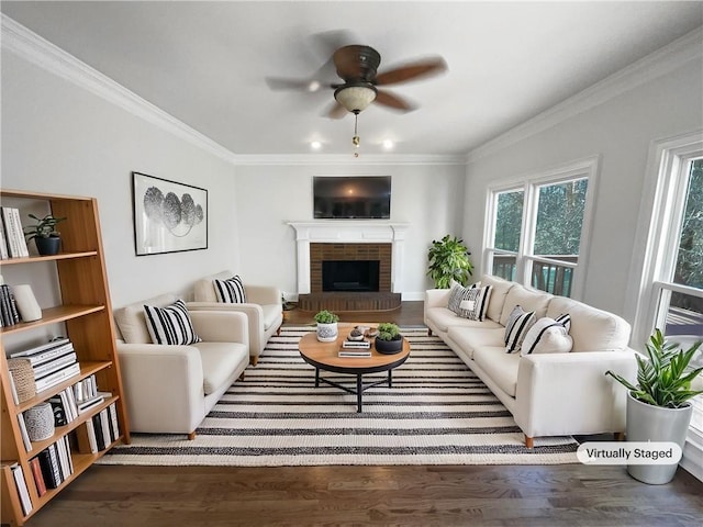 living area featuring ceiling fan, a fireplace, ornamental molding, and dark wood-style flooring