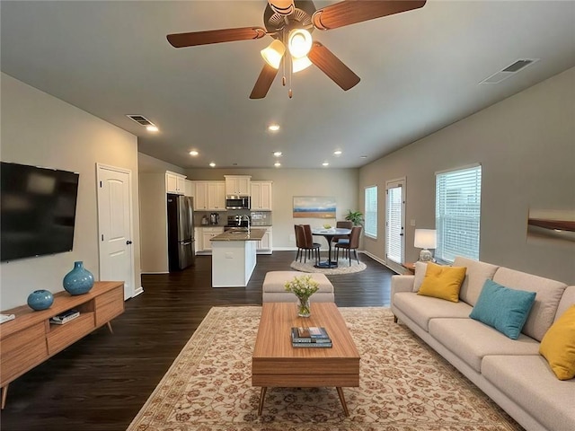 living room featuring sink, ceiling fan, and dark wood-type flooring