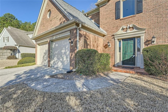 view of exterior entry with concrete driveway and brick siding