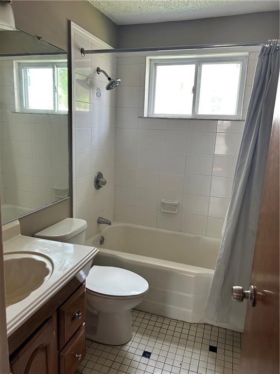 2203 Hillcrest Ave, Decatur, GA 30032 - full bathroom with tile patterned floors, toilet, shower / bath combo with shower curtain, vanity, and a textured ceiling