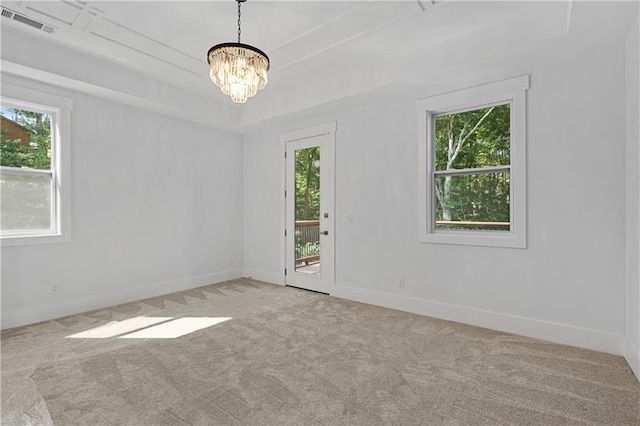 empty room featuring plenty of natural light, an inviting chandelier, and light colored carpet