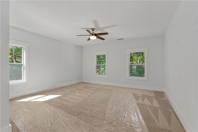 spare room featuring plenty of natural light, ceiling fan, and light colored carpet