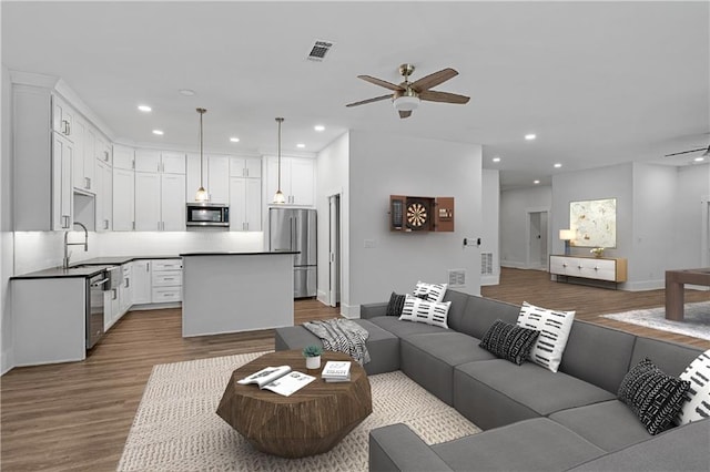 living room with light hardwood / wood-style flooring, ceiling fan, and sink