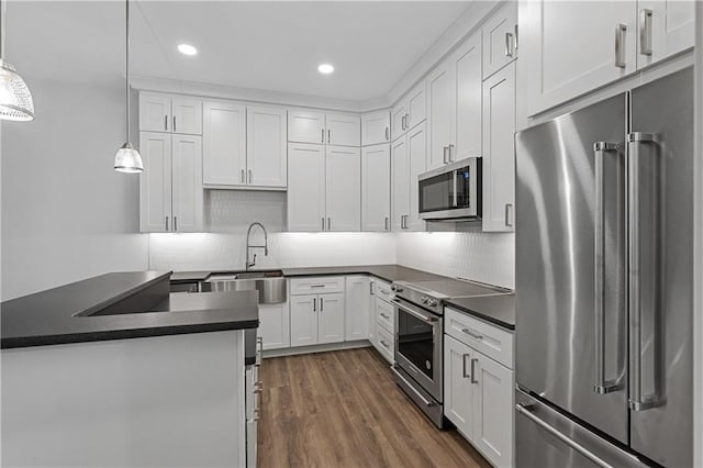 kitchen featuring white cabinetry, decorative light fixtures, dark hardwood / wood-style flooring, sink, and appliances with stainless steel finishes