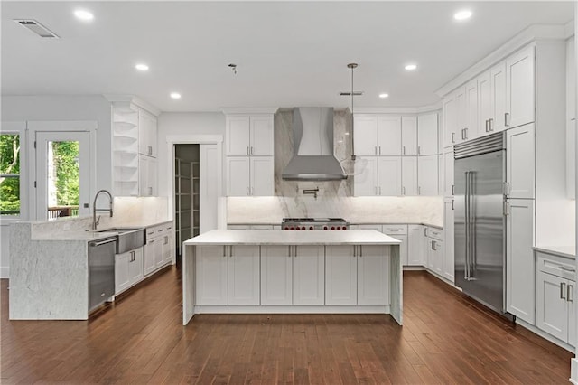 kitchen with dark hardwood / wood-style flooring, stainless steel appliances, wall chimney exhaust hood, and sink