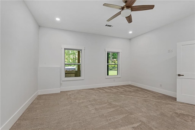 carpeted spare room featuring ceiling fan and a wealth of natural light