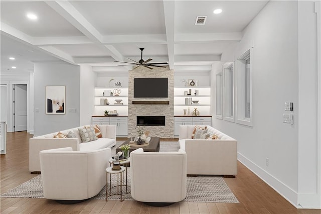 living room featuring coffered ceiling, a stone fireplace, beam ceiling, light hardwood / wood-style floors, and ceiling fan