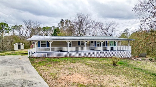 view of front of property with covered porch, metal roof, and a front lawn