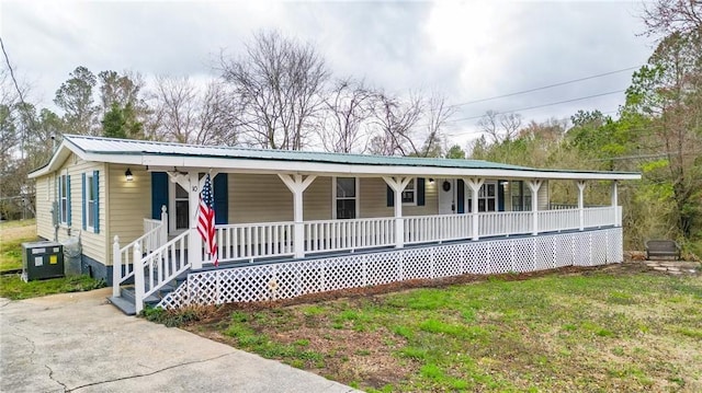 view of front of home featuring a porch, cooling unit, metal roof, and a front lawn