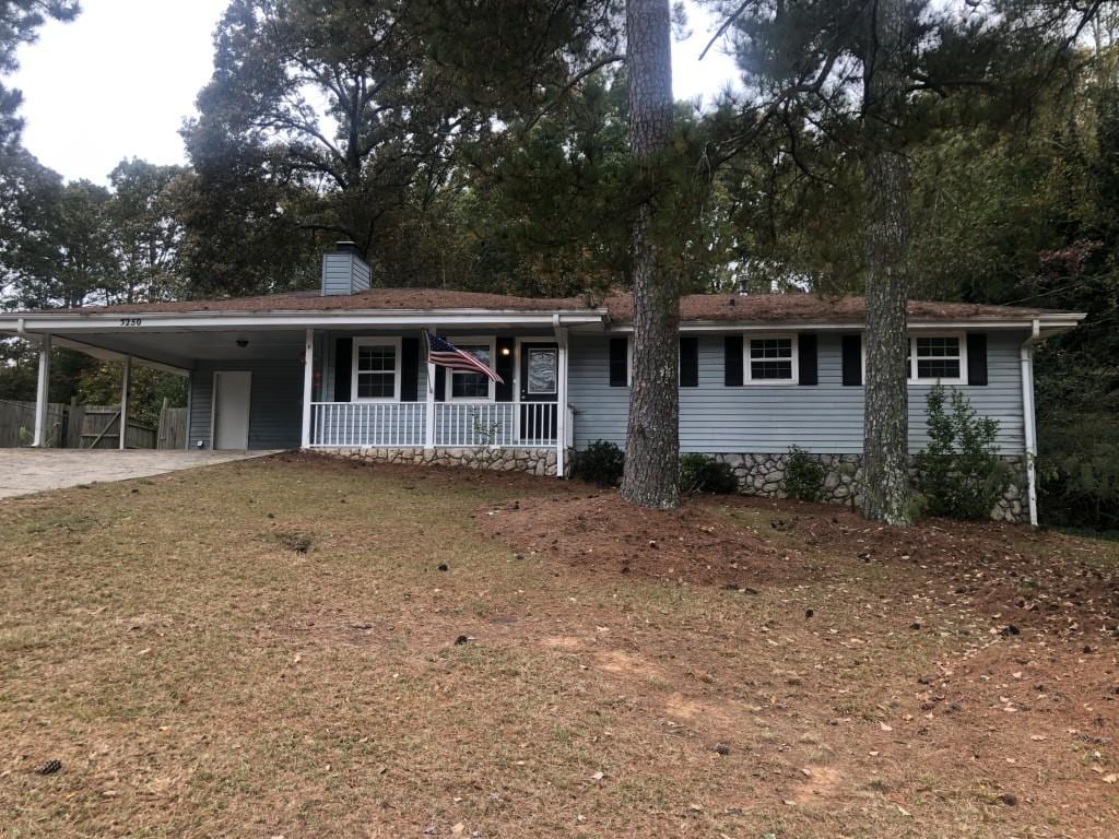 view of front of property featuring a carport, a porch, and a front yard