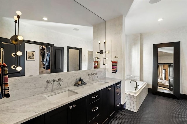 bathroom featuring tiled tub, vanity, and tile patterned flooring