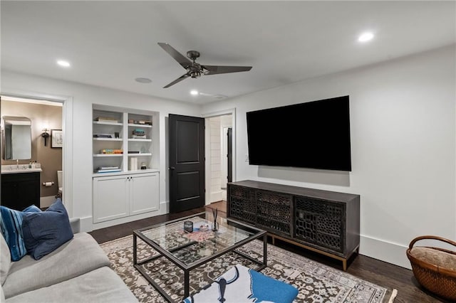 living room featuring ceiling fan, built in shelves, and dark hardwood / wood-style floors