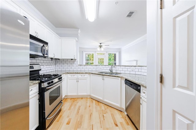 kitchen with white cabinets, stainless steel appliances, light stone counters, and sink