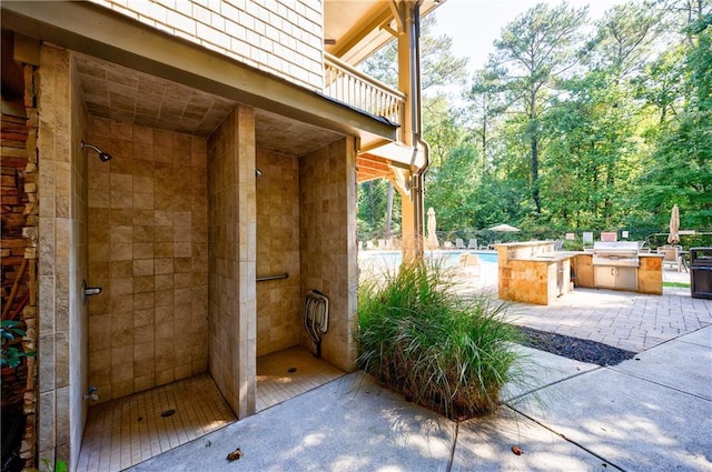 view of patio with a grill, a balcony, and exterior kitchen