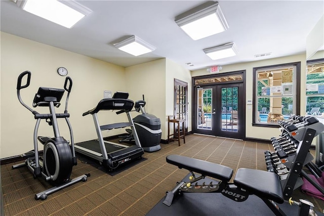 gym featuring a wealth of natural light, french doors, and dark colored carpet