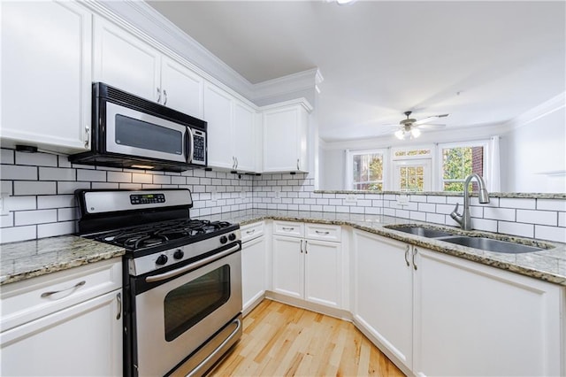 kitchen featuring decorative backsplash, white cabinetry, sink, and appliances with stainless steel finishes