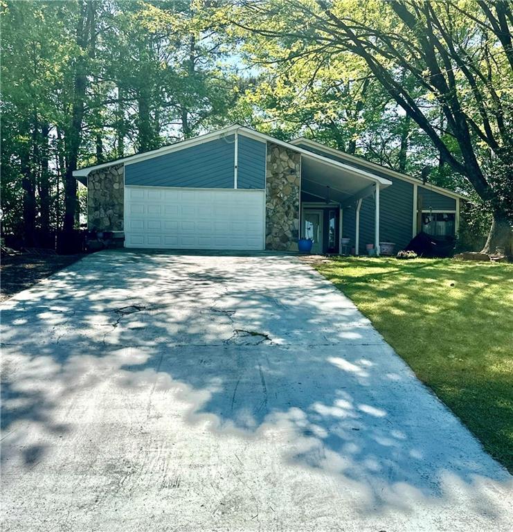 1462 Country Downs Dr, Norcross, GA 30093 - view of front of property with an attached garage, driveway, stone siding, and a front yard