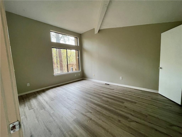 empty room with lofted ceiling with beams and hardwood / wood-style floors