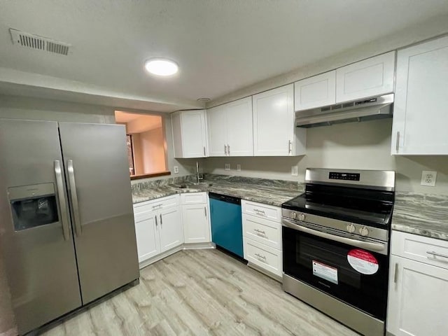 kitchen with white cabinetry, stainless steel appliances, dark stone counters, and light wood-type flooring