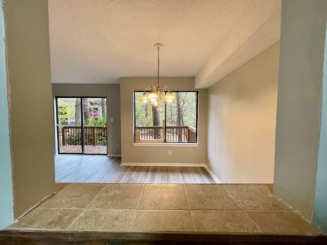 unfurnished dining area featuring a textured ceiling, wood-type flooring, and a chandelier