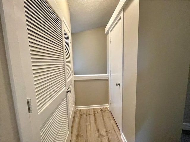 corridor featuring a textured ceiling and light wood-type flooring